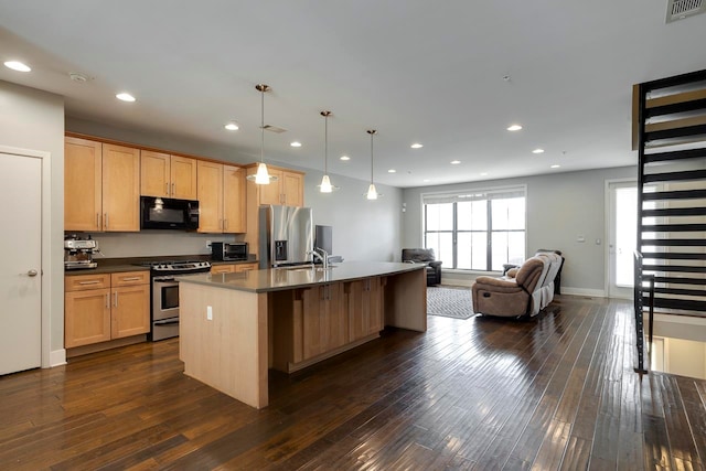 kitchen featuring dark hardwood / wood-style floors, sink, appliances with stainless steel finishes, a center island with sink, and decorative light fixtures