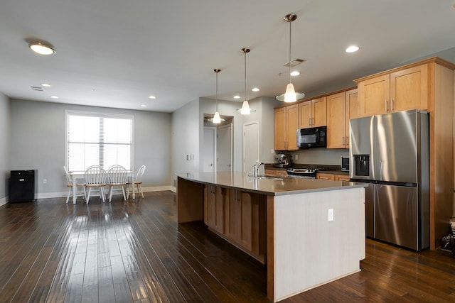 kitchen featuring an island with sink, stainless steel appliances, sink, decorative light fixtures, and dark hardwood / wood-style flooring