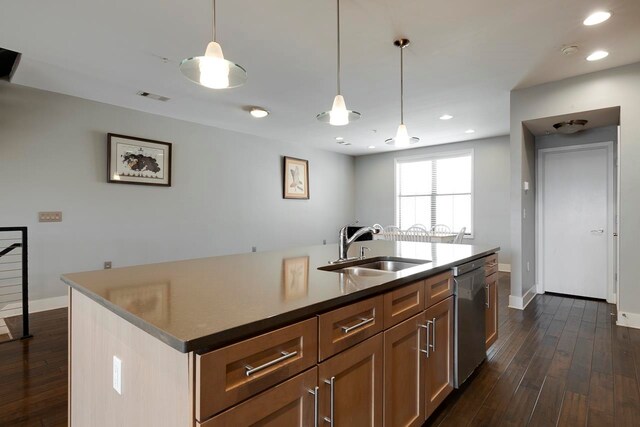 kitchen featuring decorative light fixtures, a kitchen island with sink, sink, and dark hardwood / wood-style flooring