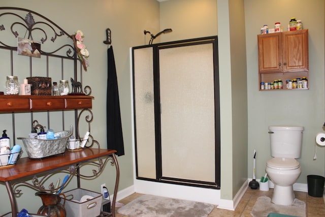 bathroom with toilet, tile floors, and a shower with door