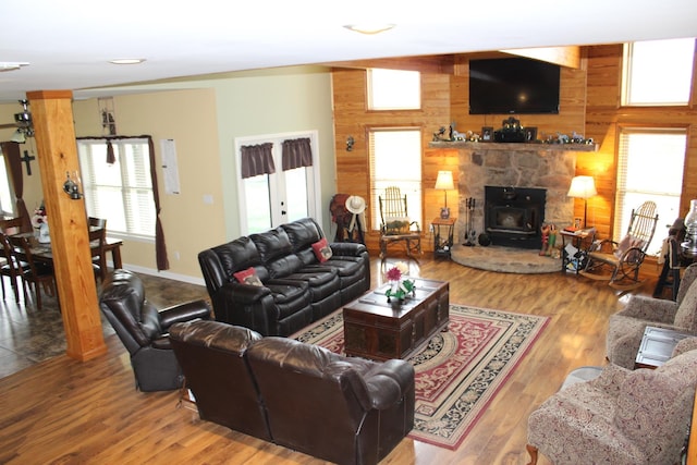 living room with wooden walls, light hardwood / wood-style flooring, and a stone fireplace