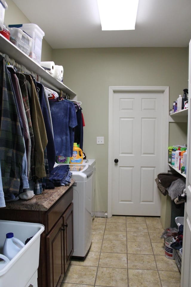 clothes washing area with cabinets, light tile floors, and washing machine and dryer