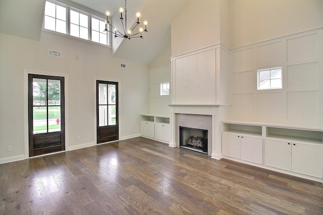 unfurnished living room featuring dark hardwood / wood-style flooring, a chandelier, and high vaulted ceiling