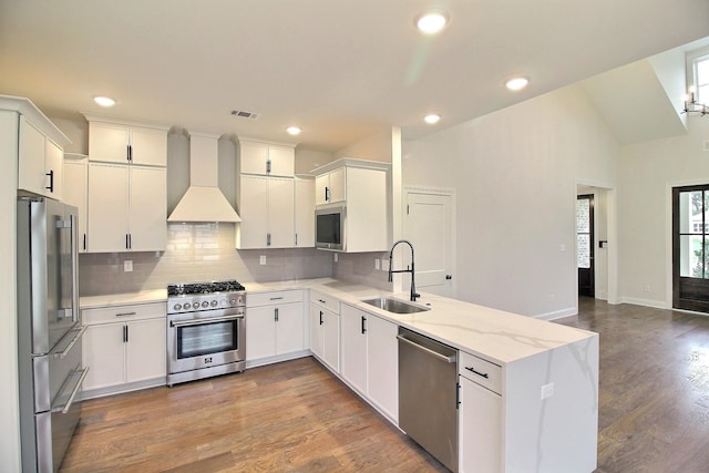 kitchen with sink, hardwood / wood-style flooring, high end appliances, and custom range hood