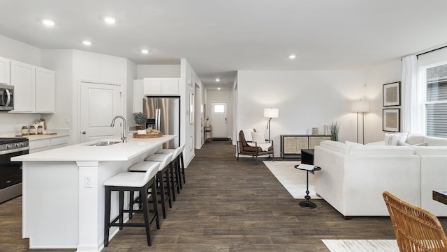 kitchen with appliances with stainless steel finishes, dark hardwood / wood-style floors, sink, and white cabinets