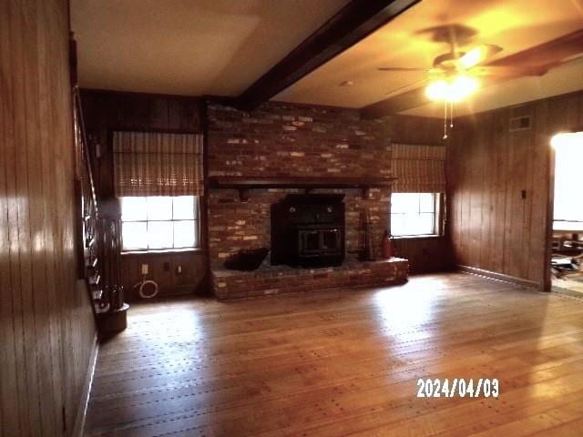 unfurnished living room featuring hardwood / wood-style flooring, plenty of natural light, and wooden walls