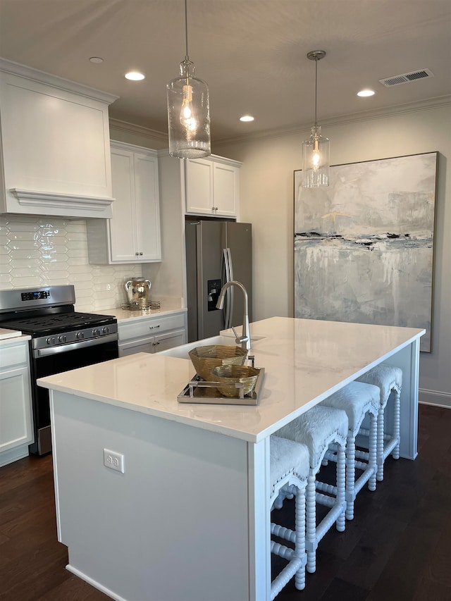 kitchen with an island with sink, stainless steel appliances, decorative light fixtures, and dark hardwood / wood-style flooring