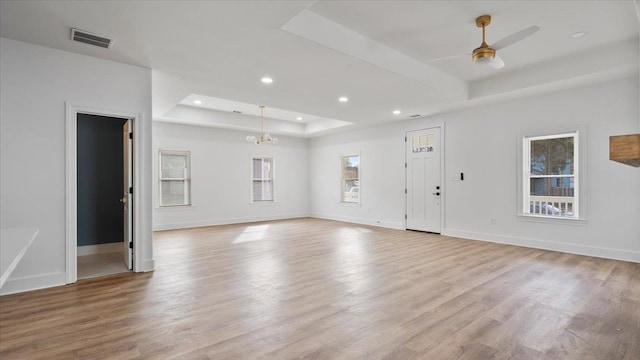 1072 Bruce St, Memphis, TN 38104 - spare room featuring a healthy amount of sunlight, light wood-type flooring, a tray ceiling, and ceiling fan with notable chandelier