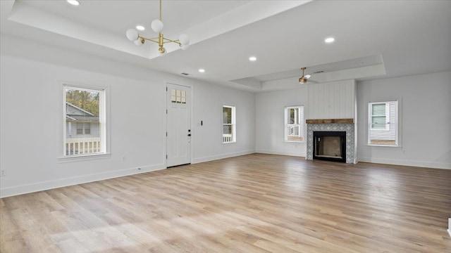 1072 Bruce St, Memphis, TN 38104 - unfurnished living room with light wood-type flooring, ceiling fan with notable chandelier, and a tray ceiling