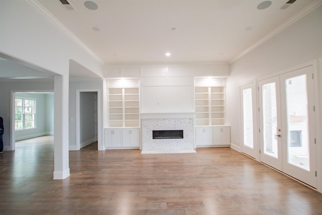 unfurnished living room with light hardwood / wood-style flooring, french doors, built in shelves, a tiled fireplace, and ornamental molding