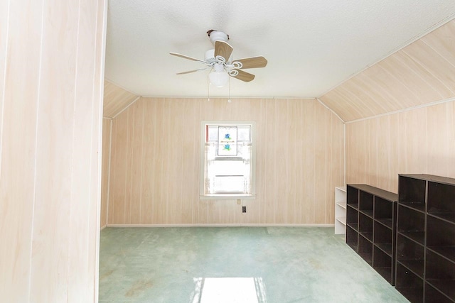 additional living space featuring ceiling fan, a textured ceiling, light carpet, vaulted ceiling, and wood walls