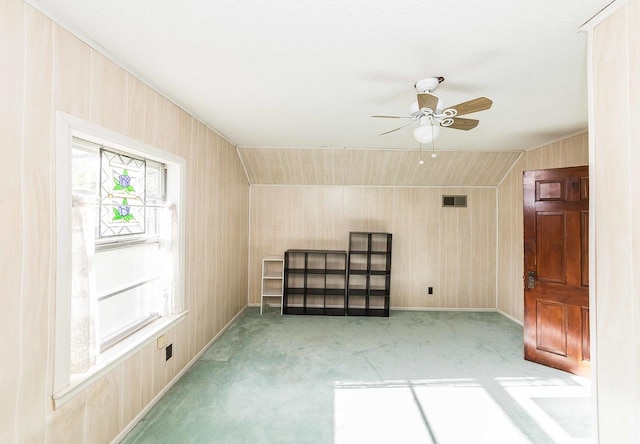 bonus room featuring ceiling fan and wooden walls