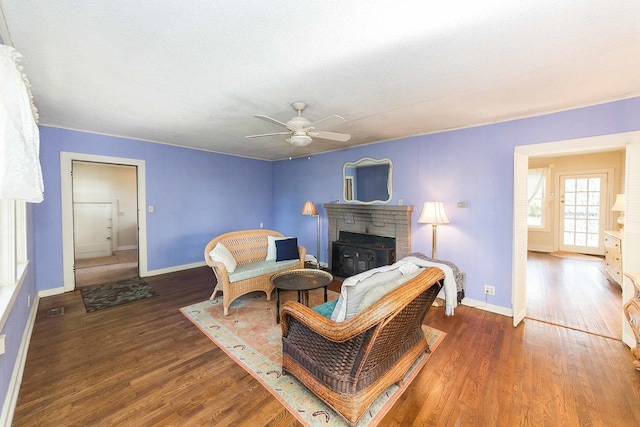 living room with dark wood-type flooring, ceiling fan, and a fireplace