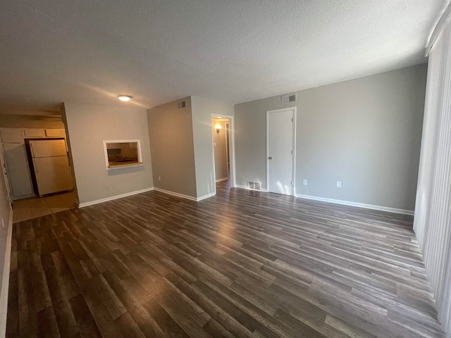 unfurnished living room featuring a textured ceiling and dark hardwood / wood-style flooring