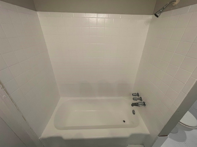 bathroom with tiled shower / bath combo and toilet