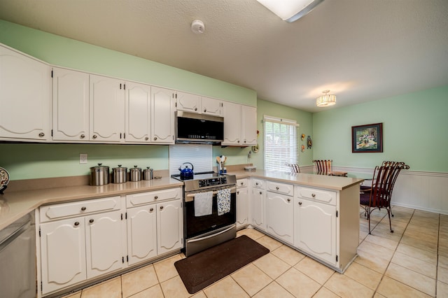 kitchen featuring appliances with stainless steel finishes, light tile floors, white cabinets, and kitchen peninsula