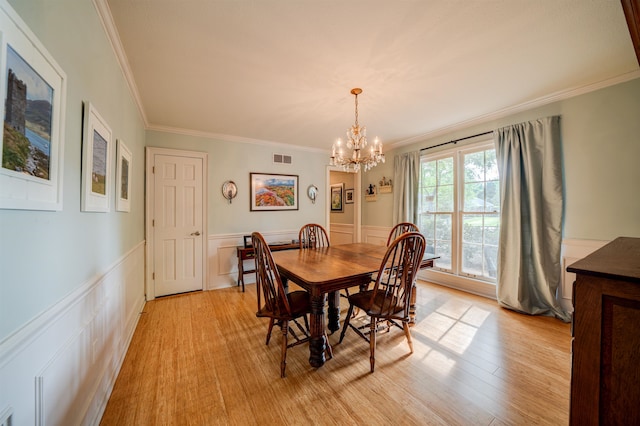 dining area with crown molding, an inviting chandelier, and light hardwood / wood-style floors