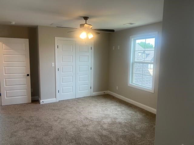 unfurnished bedroom featuring ceiling fan, carpet floors, and a closet