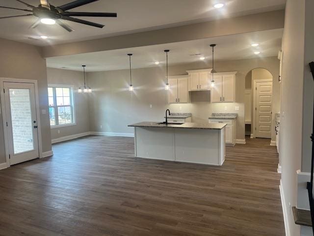 kitchen with ceiling fan, white cabinets, sink, a kitchen island with sink, and dark wood-type flooring