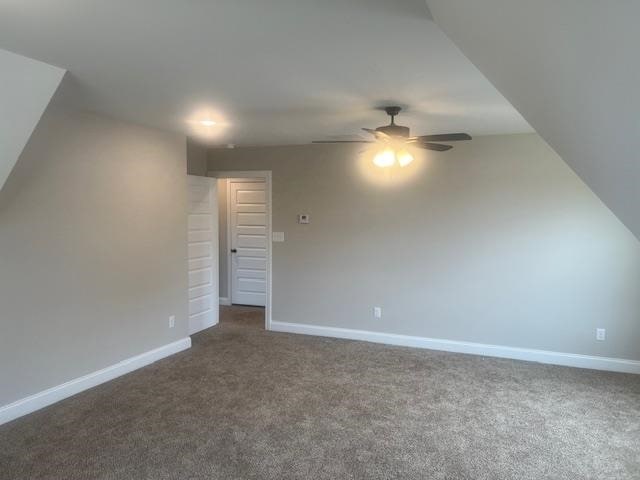 bonus room with ceiling fan and dark colored carpet