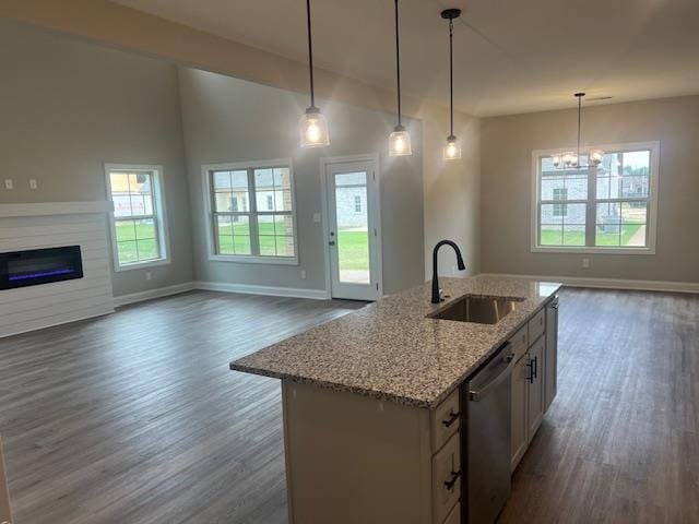 kitchen with a kitchen island with sink, dark wood-type flooring, sink, decorative light fixtures, and stainless steel dishwasher