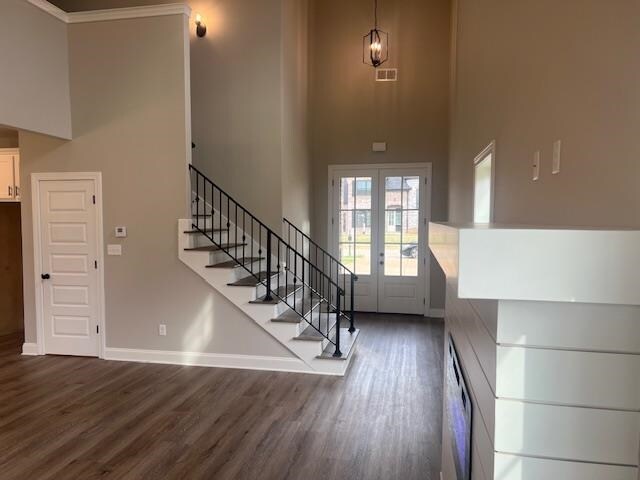 entryway featuring french doors, ornamental molding, dark wood-type flooring, and a high ceiling