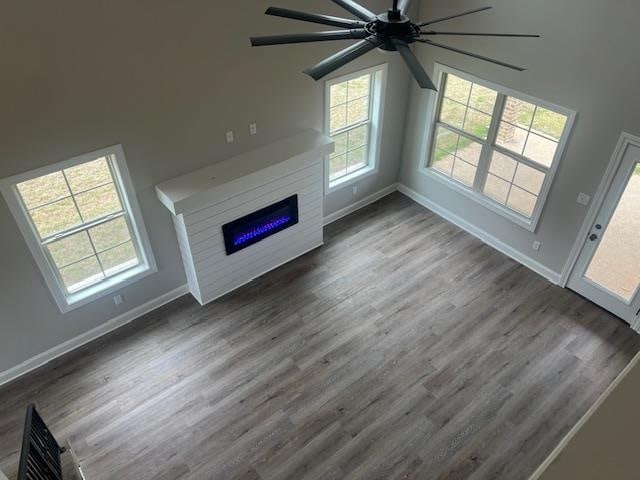 unfurnished living room with a towering ceiling, dark hardwood / wood-style flooring, and ceiling fan