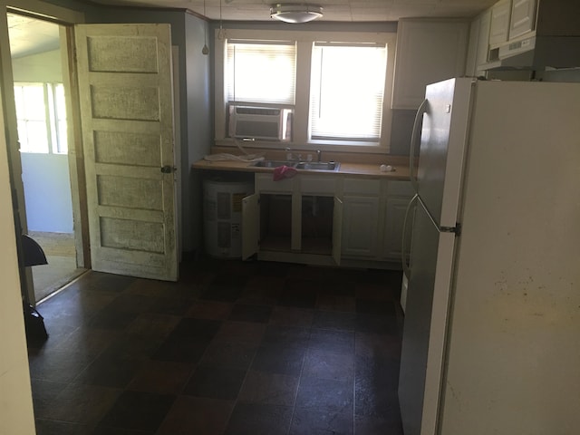 2965 Lotus Rd, Memphis, TN 38109 - kitchen featuring white refrigerator, dark tile floors, a healthy amount of sunlight, and white cabinetry