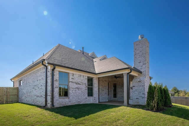 rear view of house featuring a yard and ceiling fan