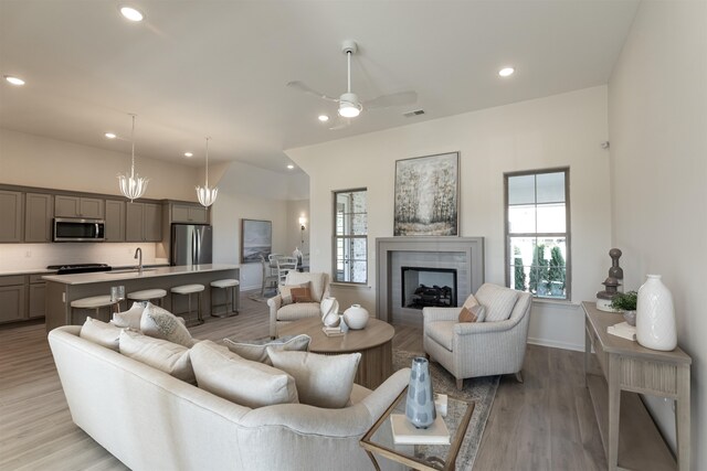 living room with ceiling fan, light hardwood / wood-style flooring, a fireplace, and sink