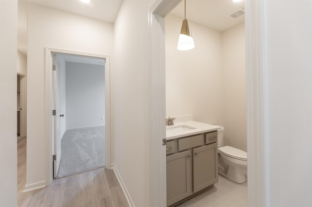 bathroom with vanity, toilet, and hardwood / wood-style flooring