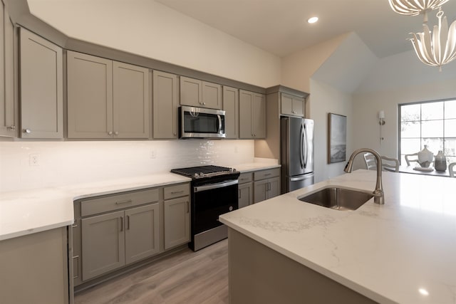 kitchen with gray cabinetry, light hardwood / wood-style flooring, sink, light stone counters, and appliances with stainless steel finishes