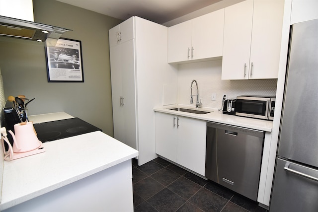 kitchen featuring appliances with stainless steel finishes, dark tile floors, sink, backsplash, and white cabinetry