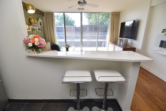 kitchen featuring dark hardwood / wood-style floors, a breakfast bar area, ceiling fan, and kitchen peninsula