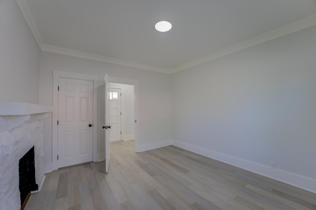 unfurnished living room featuring crown molding, light wood-type flooring, and a premium fireplace