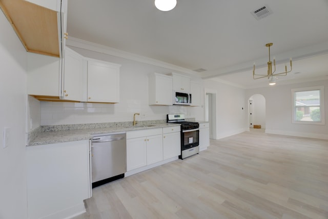 kitchen with tasteful backsplash, appliances with stainless steel finishes, light hardwood / wood-style floors, and white cabinets