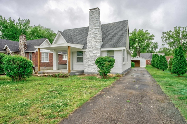 view of front of house with an outdoor structure, a garage, and a front yard