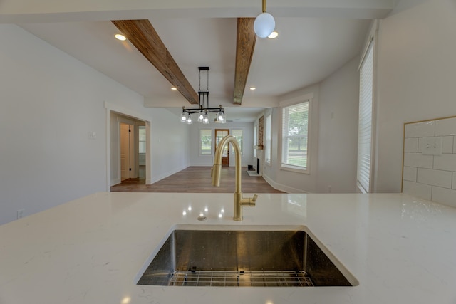 kitchen with wood-type flooring, hanging light fixtures, beamed ceiling, and sink