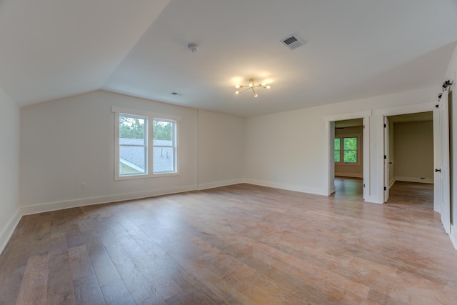 unfurnished room with hardwood / wood-style flooring, a barn door, and lofted ceiling