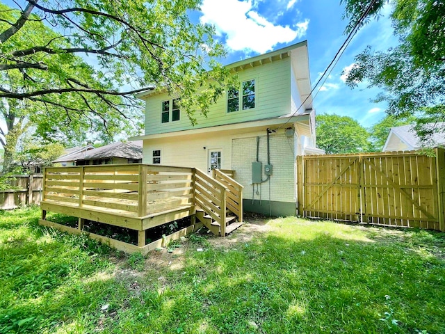 back of property featuring a deck and a lawn