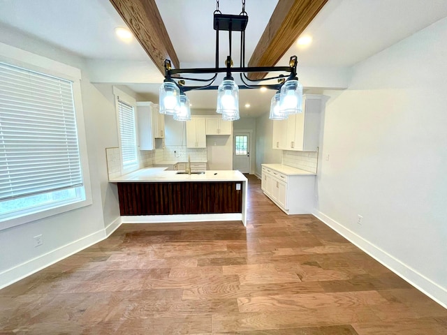 kitchen with beam ceiling, tasteful backsplash, hardwood / wood-style flooring, and pendant lighting