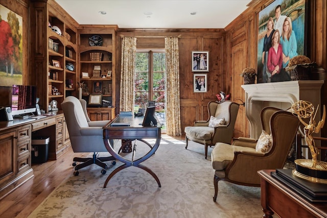 office area with hardwood / wood-style floors, built in shelves, and wooden walls