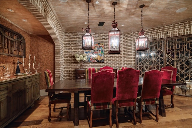 dining space featuring brick wall, light hardwood / wood-style flooring, and wooden ceiling