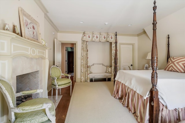 bedroom featuring a premium fireplace, hardwood / wood-style flooring, and ornamental molding