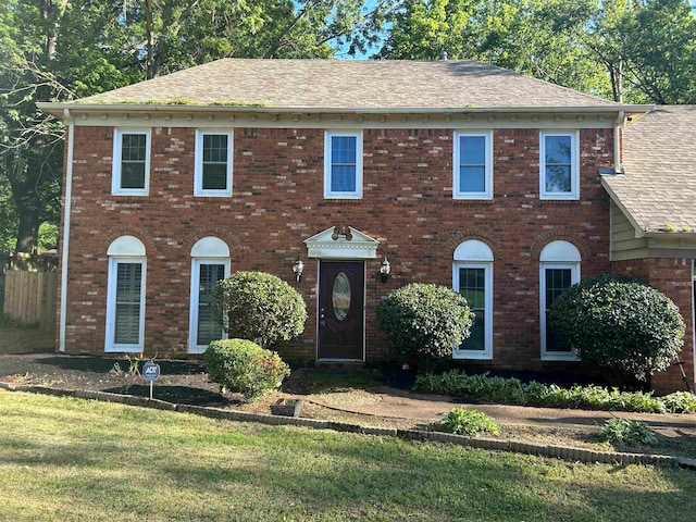 colonial-style house featuring a front yard