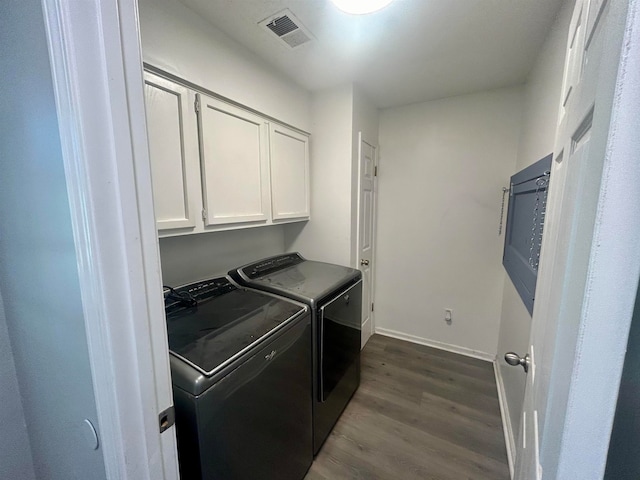 clothes washing area with separate washer and dryer, dark wood-type flooring, and cabinets