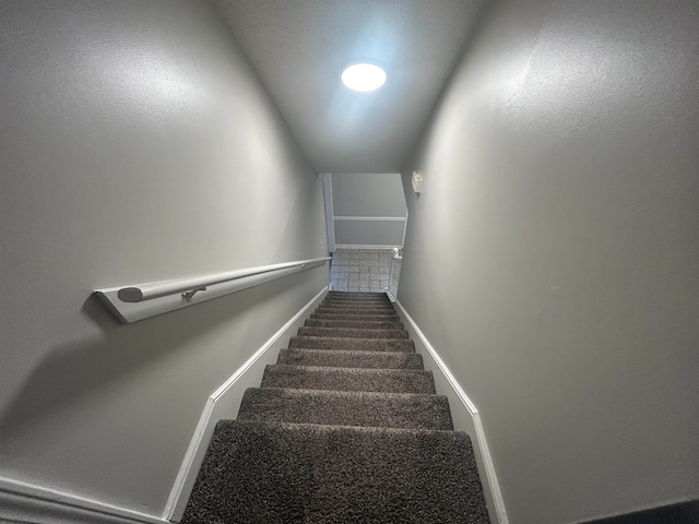 staircase featuring vaulted ceiling and carpet