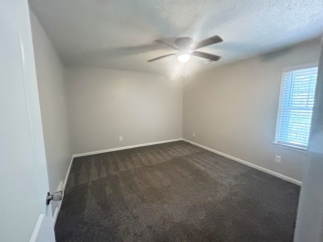 empty room featuring dark colored carpet, ceiling fan, and a textured ceiling