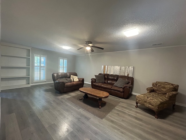 living room featuring built in features, ceiling fan, crown molding, hardwood / wood-style floors, and a textured ceiling