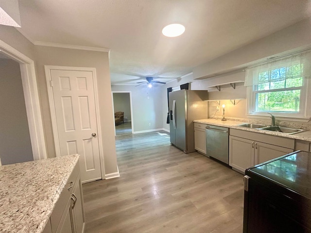 kitchen with ceiling fan, sink, stainless steel appliances, light stone countertops, and light hardwood / wood-style floors